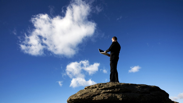 Man on rocks holding laptop up